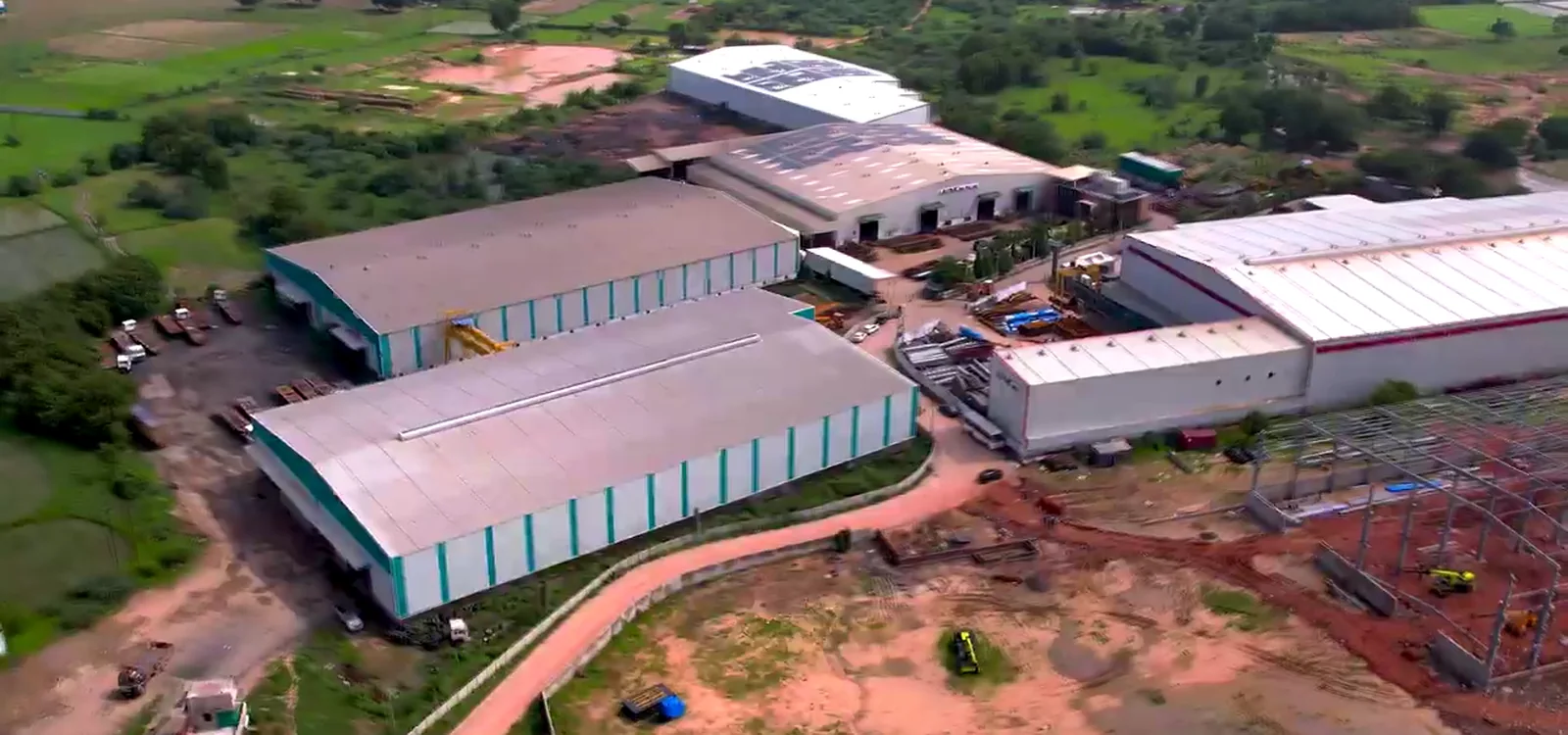 The Allmarc campus at Kanbha, Ahmedabad, from the air: the running sheds and the new shed going up beside them