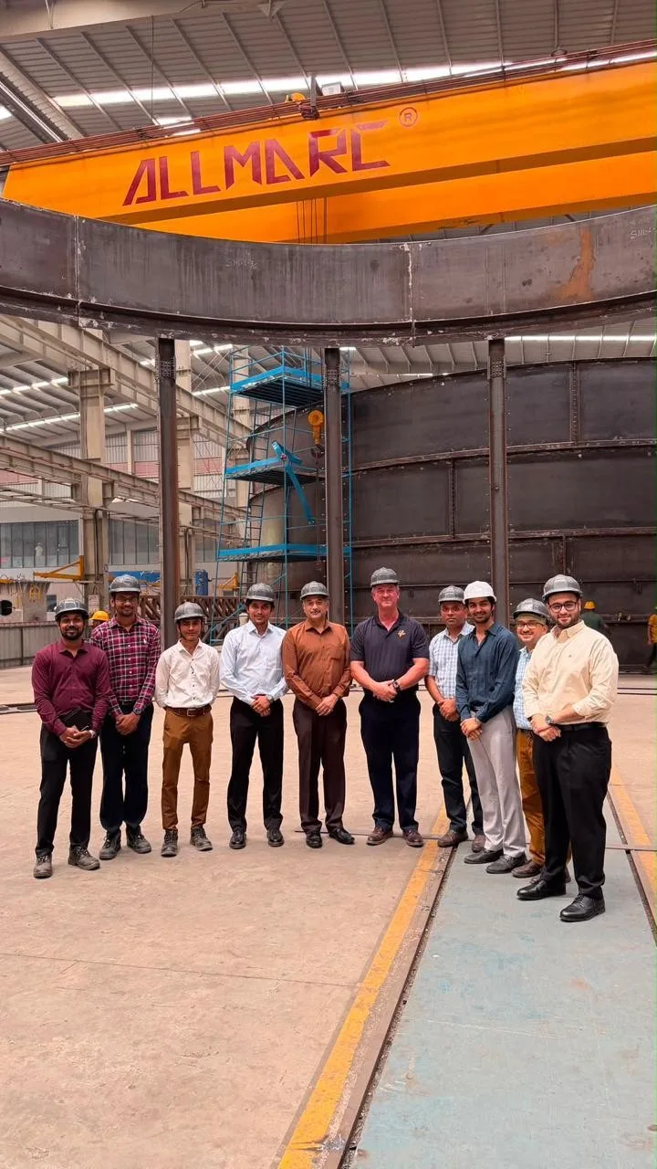 The Allmarc team standing together in the plant, under an overhead crane marked ALLMARC