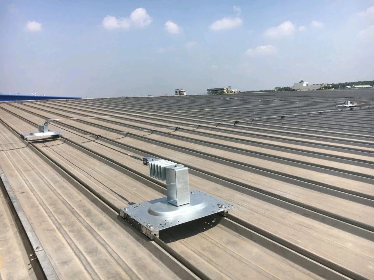 A lifeline base plate clamped to a standing-seam roof